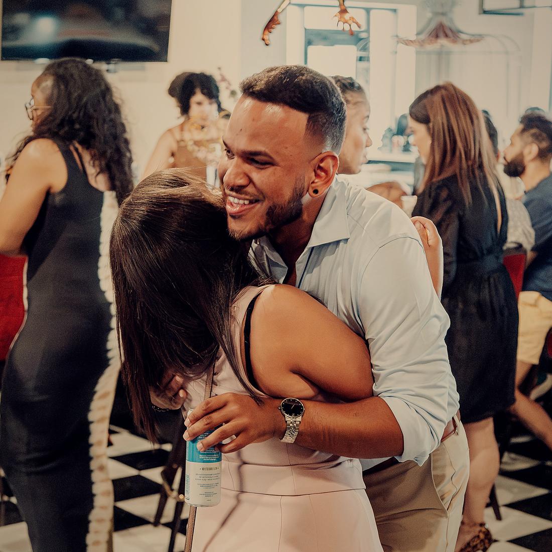 Two guests dancing close on the checkerboard floor, the room full behind them.