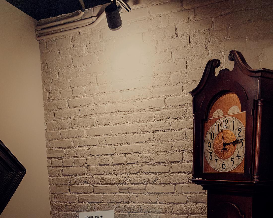 A quiet corner: the tall clock against the white brick wall.