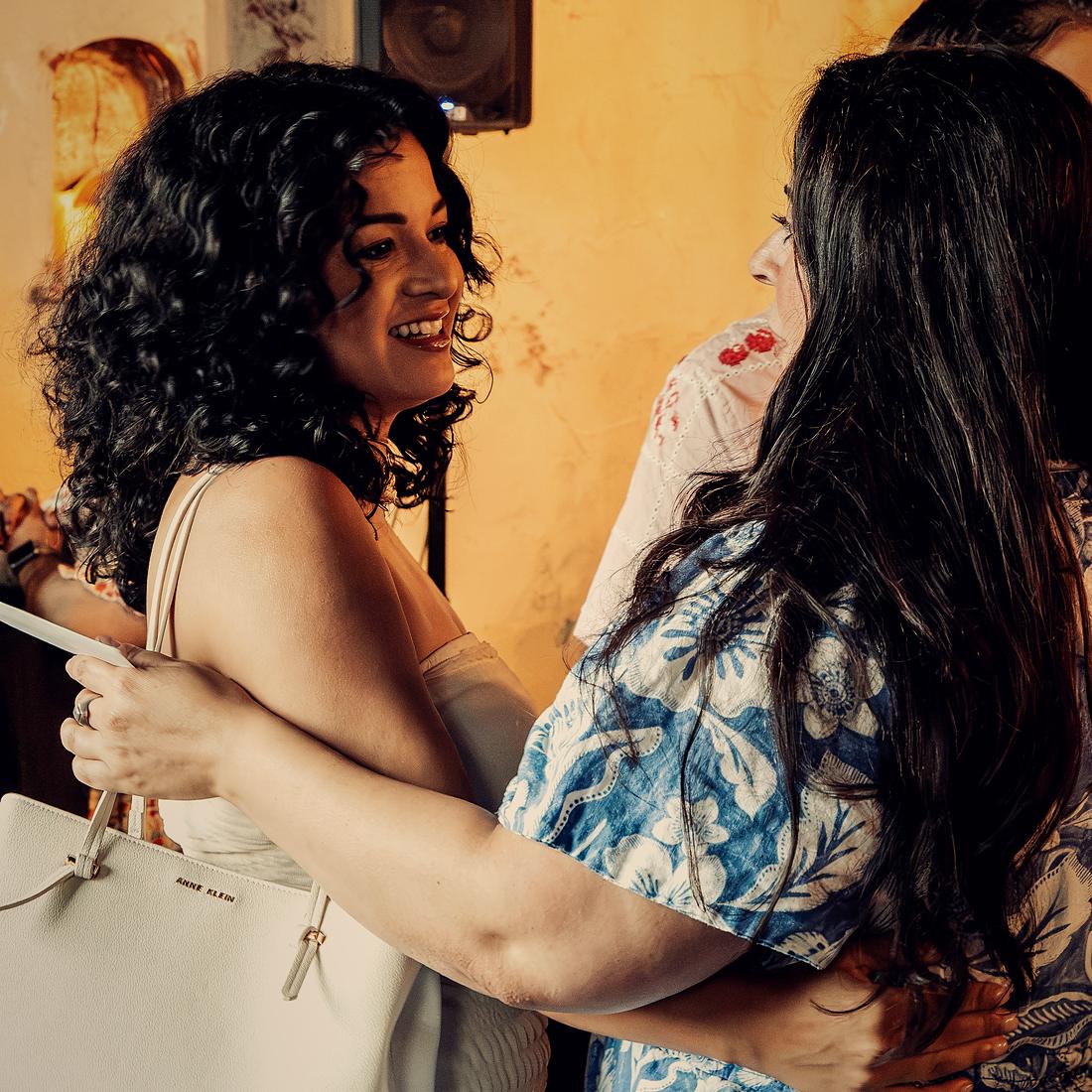 An embrace between friends beside the tall tables.