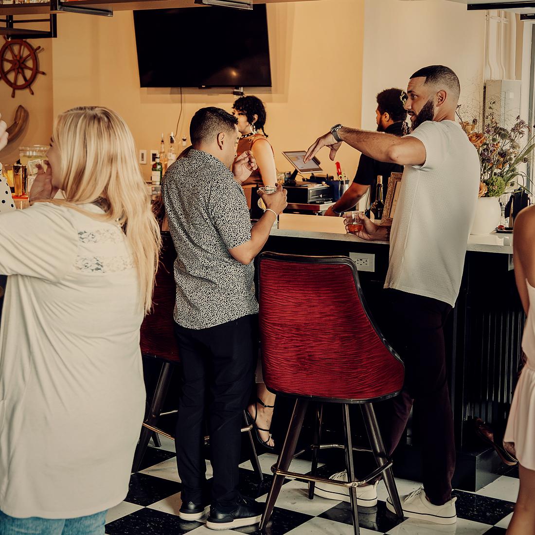 Bartenders working the bar while guests wait on the other side.