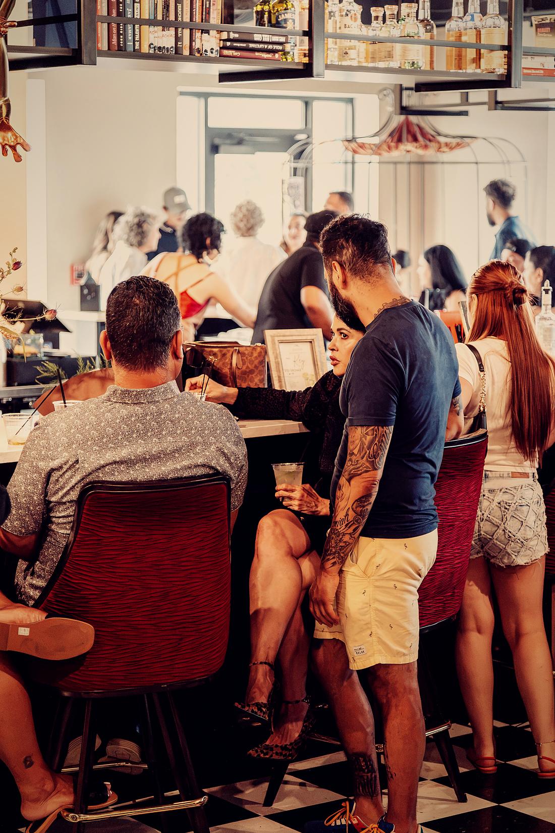 Guests gathered at the tall tables, red velvet chairs and the bar behind them.